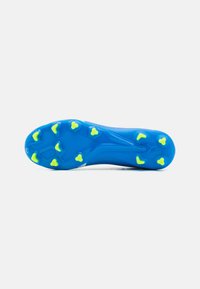 Suela de botas de fútbol azul con tacos triangulares amarillos, superficie texturizada lisa y forma curvada y ergonómica para una mejor tracción.