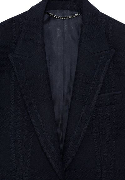 Marineblaue Strickjacke mit notch-Kragen, satiniertem Innenfutter und einem silbernen Kettendetail am Kragen. Mit einer Brusttasche.