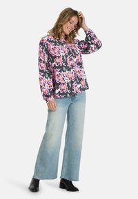 Floral-print top with long sleeves in black, pink, and white. Paired with light-wash wide-leg jeans and black ankle boots.