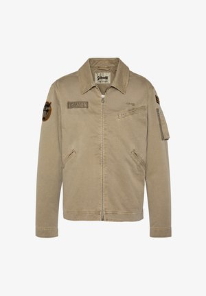 Veste beige à fermeture éclair avec col, patchs sur la poitrine et les manches, poche poitrine zippée et deux poches frontales inférieures, fabriquée par Schott.