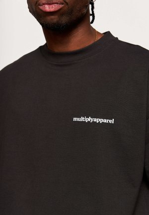 Zwart katoenen T-shirt met een ronde hals en een wit logo "multiplyapparel" gedrukt op de linkerborst. Soepele textuur.