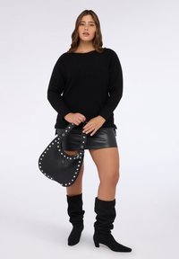 Maglione nero a maglia con vestibilità ampia, abbinato a una minigonna in pelle nera. Accessoriato con una borsa borchiata nera e stivali neri al ginocchio.