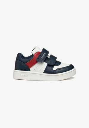 Sneaker in pelle blu navy e bianca con dettagli rossi, cinturini in velcro, lati perforati e suola in gomma bianca testurizzata. Nome del marchio visibile.