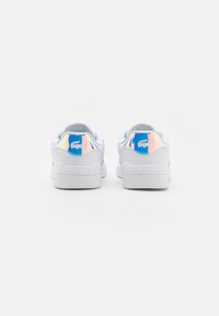 Baskets blanches avec tige en cuir lisse, présentant un accent irisé brillant sur le talon et un détail logo. Semelle plate en caoutchouc.