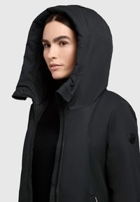 Czarna ocieplana kurtka z wysokim kołnierzem i dużym kapturem. Posiada zamek błyskawiczny, boczne kieszenie oraz naszywkę z logo na rękawie.