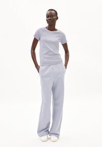 Licht asblauw geribbeld t-shirt met korte mouwen, gecombineerd met bijpassende wijde broek, beide in zachte stof. Gemaakt met witte sneakers.