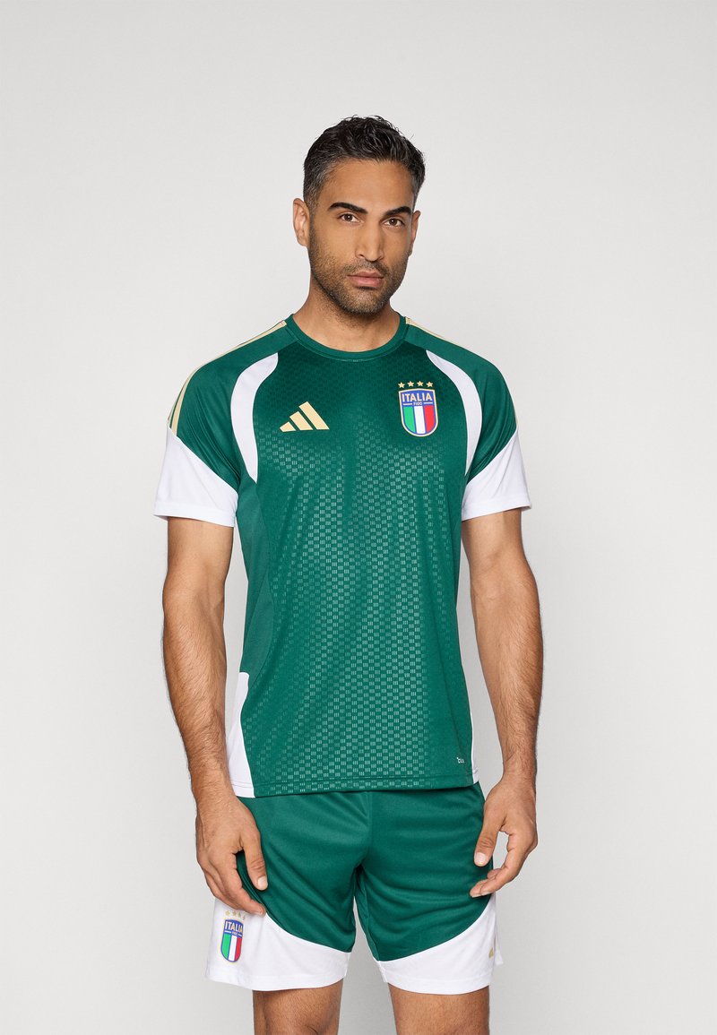 Camisa de desporto verde com detalhes brancos e dourados. Apresenta o emblema da bandeira italiana e uma textura em malha. Acompanhada de calções combinando.