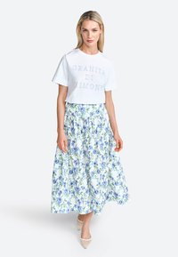 White t-shirt with "Granita di Limone" text, paired with a long floral skirt featuring blue and green patterns on a white background.