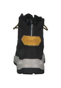 Zwarte mid-top sneaker met een textuur bovenwerk, gele accenten op de hak, een reflecterende strip en een stevige grijze buitenzool. Beschikt over duurzame materialen.