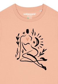 T-shirt en coton couleur pêche avec un dessin abstrait en ligne noire d'une figure assise avec un cœur, entourée de feuillages et de formes géométriques.