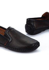 Schwarze Leder-Schlupfschuhe mit durchbrochenem Design, abgerundetem Zeh, kontrastierenden Nähten und strukturierten Akzenten an der Ferse.