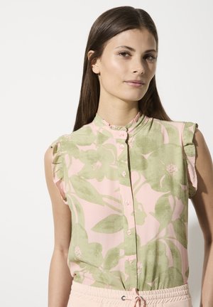 Kurzärmlige, hellrosa Bluse mit grünem Blumenmuster, knopfbarer Vorderseite und Rüschenausschnitt. Weicher Stoff mit glatter Textur.