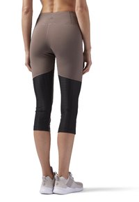 Legginsy kapri w kolorze brązowym i czarnym, wykonane z elastycznego materiału, z teksturowanym czarnym dolnym panelem i średnim stanem. Zawierają detal z logo.