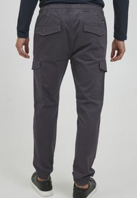 Grijze cargobroek met elastische tailleband, ribbel manchetten en meerdere zakken. Gemaakt van een soepele stof met een matte afwerking.