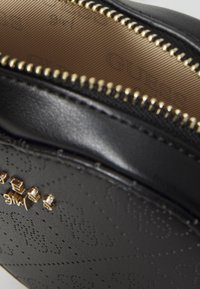 Borsa a tracolla nera in finta pelle con chiusura a zip, caratterizzata da una zip dorata e un motivo stampato. Interno foderato in tessuto beige.