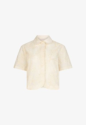 Blouse crème à manches courtes avec broderie florale texturée, boutonnage devant et ourlet arrondi.