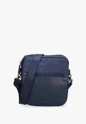 Navy crossbody bag featuring a combination of smooth and textured fabric, adjustable strap, front zipper pocket, and logo detail.