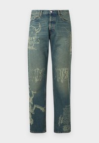 Vaqueros de mezclilla con estampados gráficos descoloridos que incluyen una calavera con cuernos que fuma, texto abstracto y un esqueleto en las piernas, vista frontal.