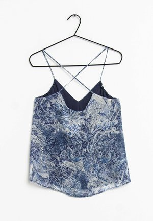 Haut sans manches à motif floral bleu et blanc avec fines bretelles croisées, suspendu à un cintre en fil noir.