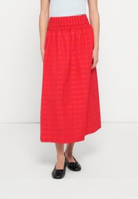 Czerwona spódnica do kolan z marszczonym elastycznym pasem i subtelnym, kratkowanym wzorem. Materiał wydaje się gładki i lekki.
