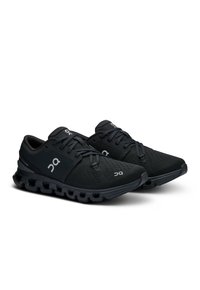 Chaussures de course noires avec une tige texturée, fermeture à lacets et semelle rembourrée distinctive avec des segments visibles pour l'absorption des chocs.