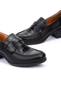 Mocasines de piel negra con un frontal texturizado con patrón de cocodrilo y acentos cosidos. Presenta un bajo tacón bloque y un forro interior suave.