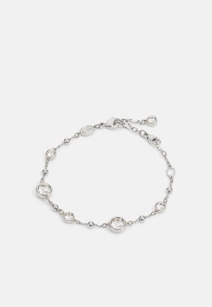 Srebrna narukvica s kružnim i sfernim akcentima, između kojih su prozirni kamenčići. Podesivi kopča s malim privjeskom.