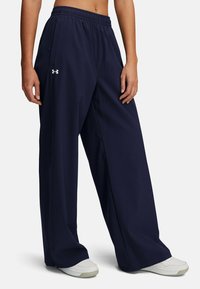 Marineblauwe, lichte wijde pantalons met een elastische tailleband en zijzak, gemaakt van een zachte, gladde stof. Beschikt over een logo detail.