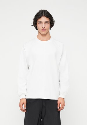 Maglietta bianca a maniche lunghe con collo rotondo e maniche raglan. Realizzata in un materiale morbido e liscio, presenta un design semplice senza motivi.