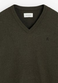 Suéter de punto suave en verde oscuro con cuello en pico, que presenta un cuello acanalado y un pequeño logotipo bordado en el pecho.