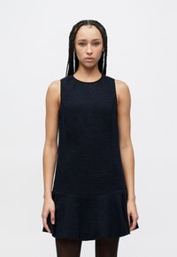 Temno modra obleka z brezrokavnim krojem, okroglim izrezom in nabrano spodnjo robom. Material deluje mehak in rahlo oblikovan.