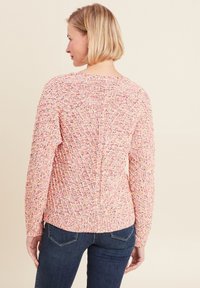 Texturiertes pinkes Sweatshirt mit mehrfarbigen Einsprengseln. Verfügt über lange Ärmel und einen leicht geschwungenen Saum. Weicher Stoff mit einem gestrickten Muster.