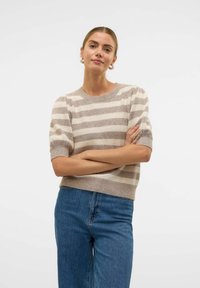 Pull en maille rayé beige et marron clair avec manches courtes bouffantes, encolure ronde et coupe décontractée, associé à un jean taille haute bleu.