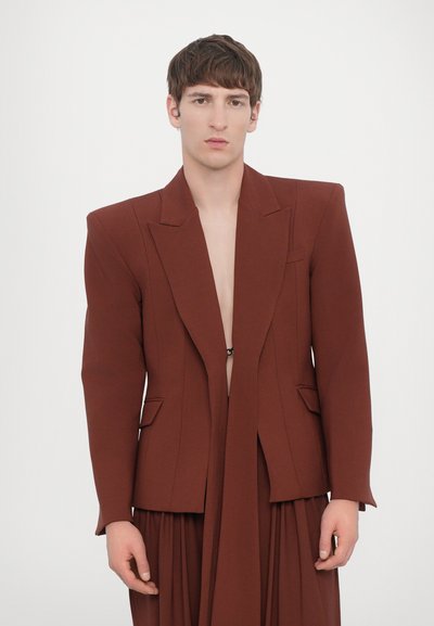 Blazer maro personalizat cu rever ascuțit, închidere cu un singur nasture și deschidere frontală. Include buzunare laterale și pantaloni largi maro complementar.