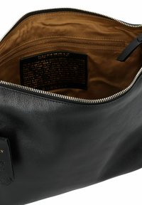 Borsetta in pelle nera con chiusura a zip, caratterizzata da un esterno liscio e foderata in tessuto color nocciola. Include una tasca interna con zip e un'etichetta con il marchio.
