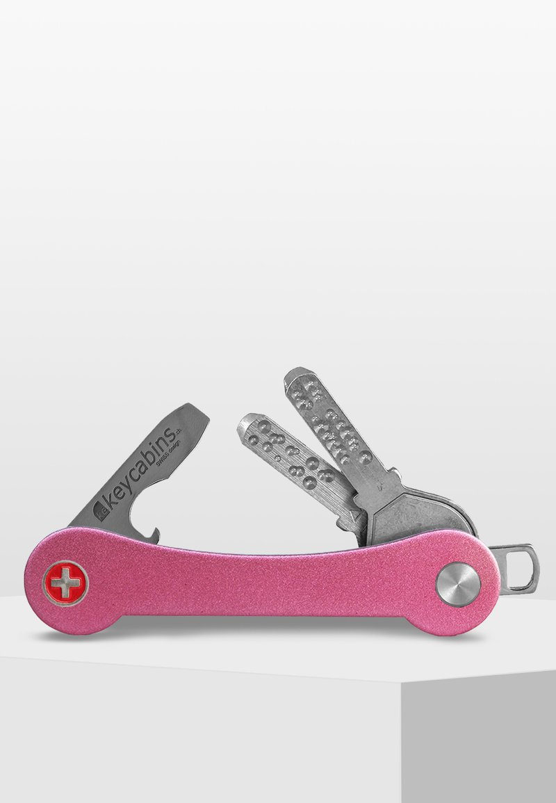 Rosa metallmultiverktyg med rundad kropp, med silverfärgade nycklar, en spårskruvmejsel och en nyckelring. Texten på huvudbladet säger "keycabins."