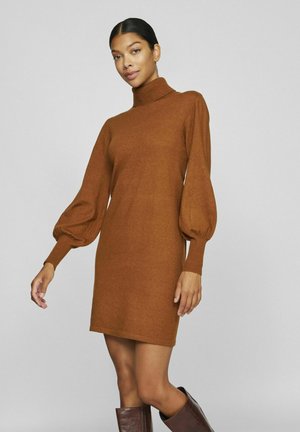 Robe en tricot marron avec un col montant et des manches longues bouffantes. Texture douce et coupe décontractée, se terminant au milieu de la cuisse. Assortie à des bottes marron jusqu'au genou.