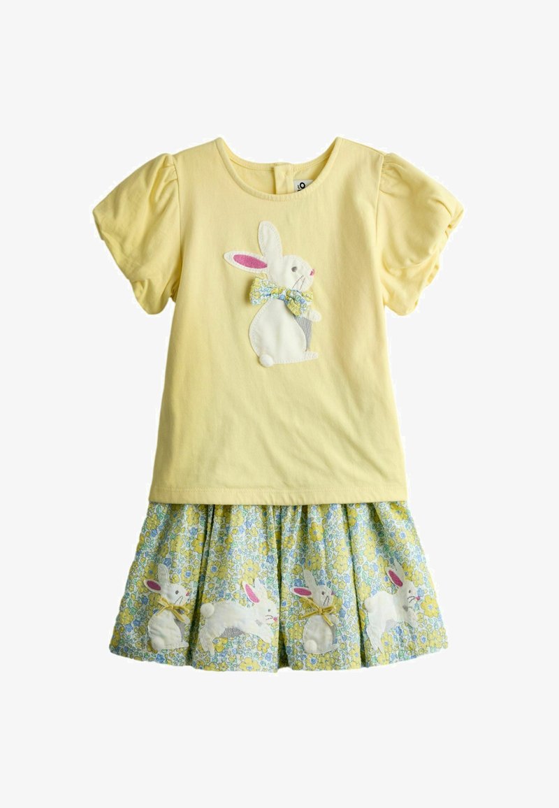 Żółta sukienka z krótkimi, bufkami na rękawach, z białym króliczkiem z kwiatową kokardą na piersi oraz kwiatowym dołem z kilkoma króliczkami.