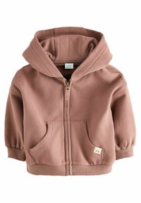 Veste zippée à capuche en rose poussiéreux, fabriquée en tissu doux. Elle présente des poignets côtelés, deux poches avant et une petite étiquette de logo en bas.