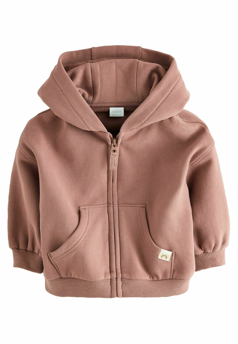 Veste zippée à capuche en rose poussiéreux, fabriquée en tissu doux. Elle présente des poignets côtelés, deux poches avant et une petite étiquette de logo en bas.