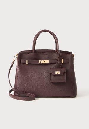Burgundy leather handbag with a structured shape, short handles, detachable shoulder strap, and a gold lock detail with a mini pouch.