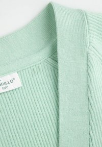 Jasnozielony sweter z prążkowanym kołnierzem, charakteryzujący się gładką fakturą i szerokim krojem. Widoczna metka z nazwą marki i rozmiarem.