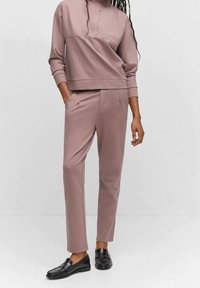 Sudadera de cuello alto y manga larga en color rosa, combinada con pantalones ajustados a juego; confeccionada en una tela suave con bolsillos y un corte holgado.