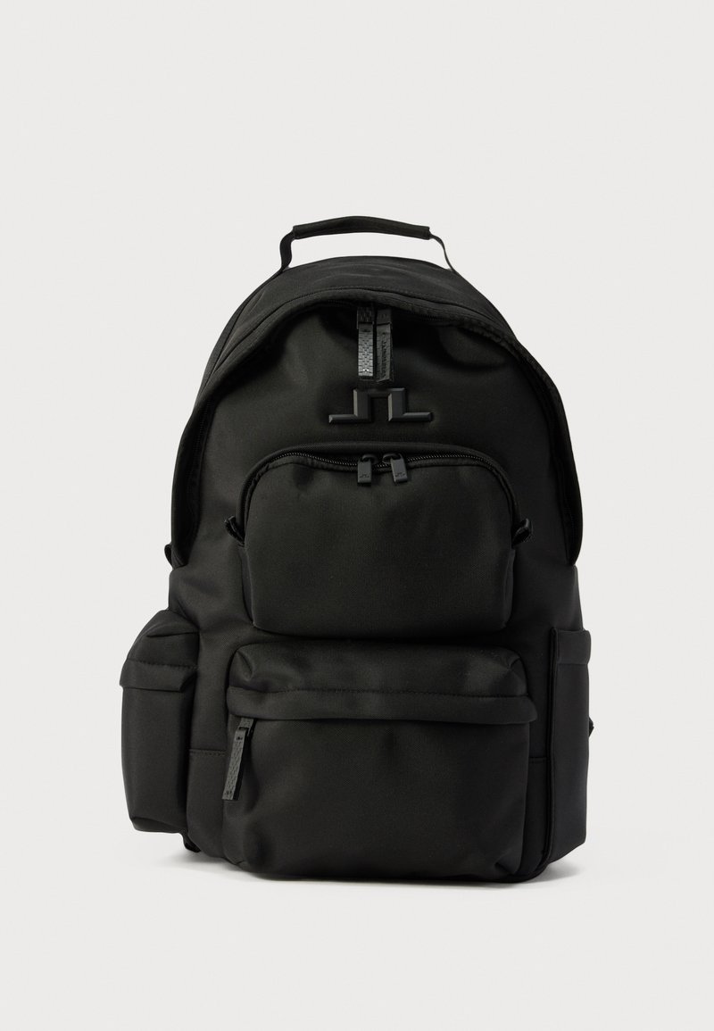 Μαύρο σακίδιο από νάιλον με πολλαπλές θήκες με φερμουάρ και πάνω λαβή, απεικονίζεται σε απλό φωτεινό φόντο.