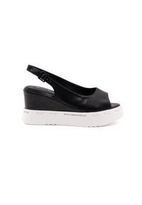 Sandalo con zeppa in pelle nera, con punta aperta, cinturino alla caviglia e suola bianca testurizzata con dettagli di branding.