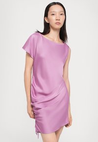 Robe en satin rose vif avec des manches courtes, coupe ample, et détail de cordon sur le côté pour un ajustement de la longueur de l'ourlet. Texture lisse et brillante.