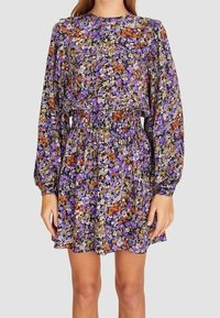 Vestido de manga larga y cintura elástica, con un denso estampado floral en púrpura, naranja y verde sobre un fondo claro.