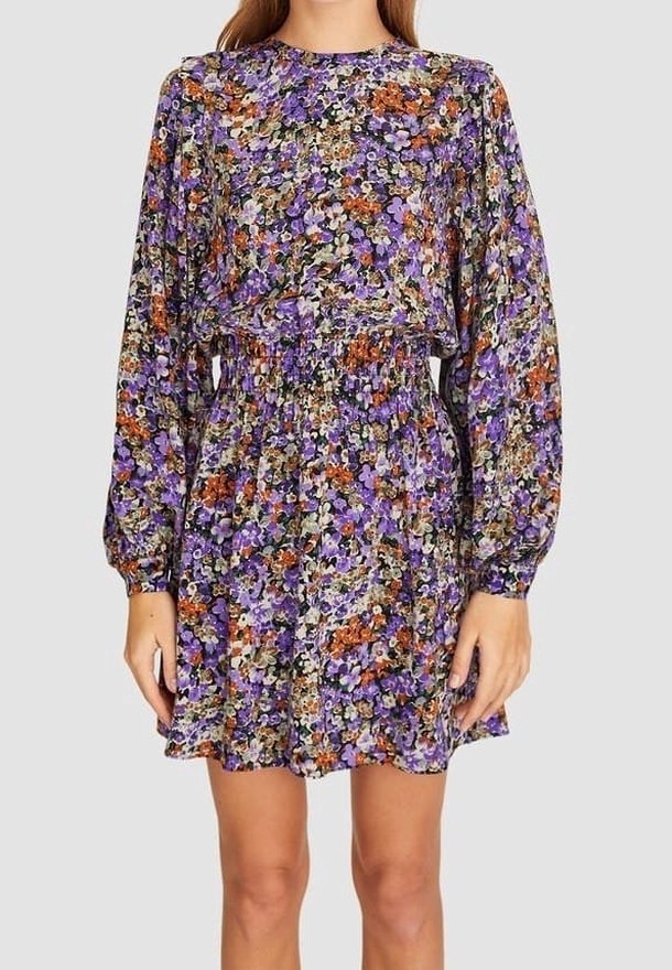Vestido de manga larga y cintura elástica, con un denso estampado floral en púrpura, naranja y verde sobre un fondo claro.
