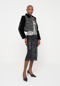 Must musta kaelusega denim-jakk, lilleline topp ja tumesinine sädeluspenskjakk. Mustad terava ninaga kingad lõpetavad komplekti.