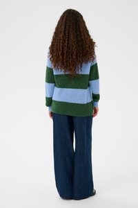 Pull coloré à blocs avec des rayures alternées vertes et bleu clair, fabriqué à partir d'un tissu doux et texturé ; associé à un jean foncé à jambes larges.